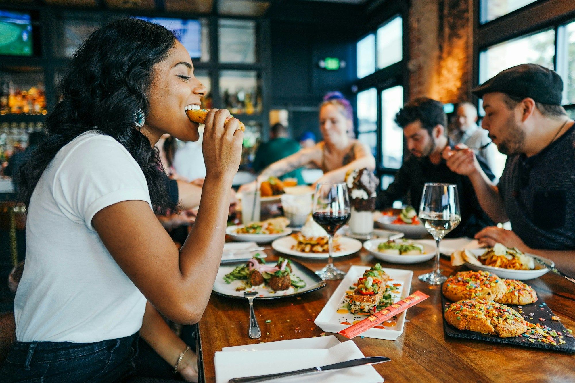 Clients attablés dans un restaurant animé, assiettes et verres sur la table