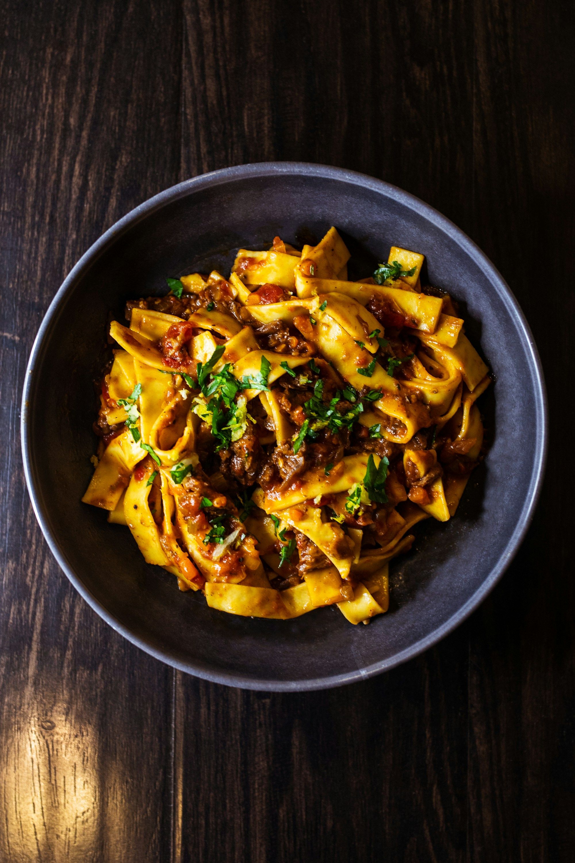 Pappardelle au ragoût servies dans une assiette creuse sombre