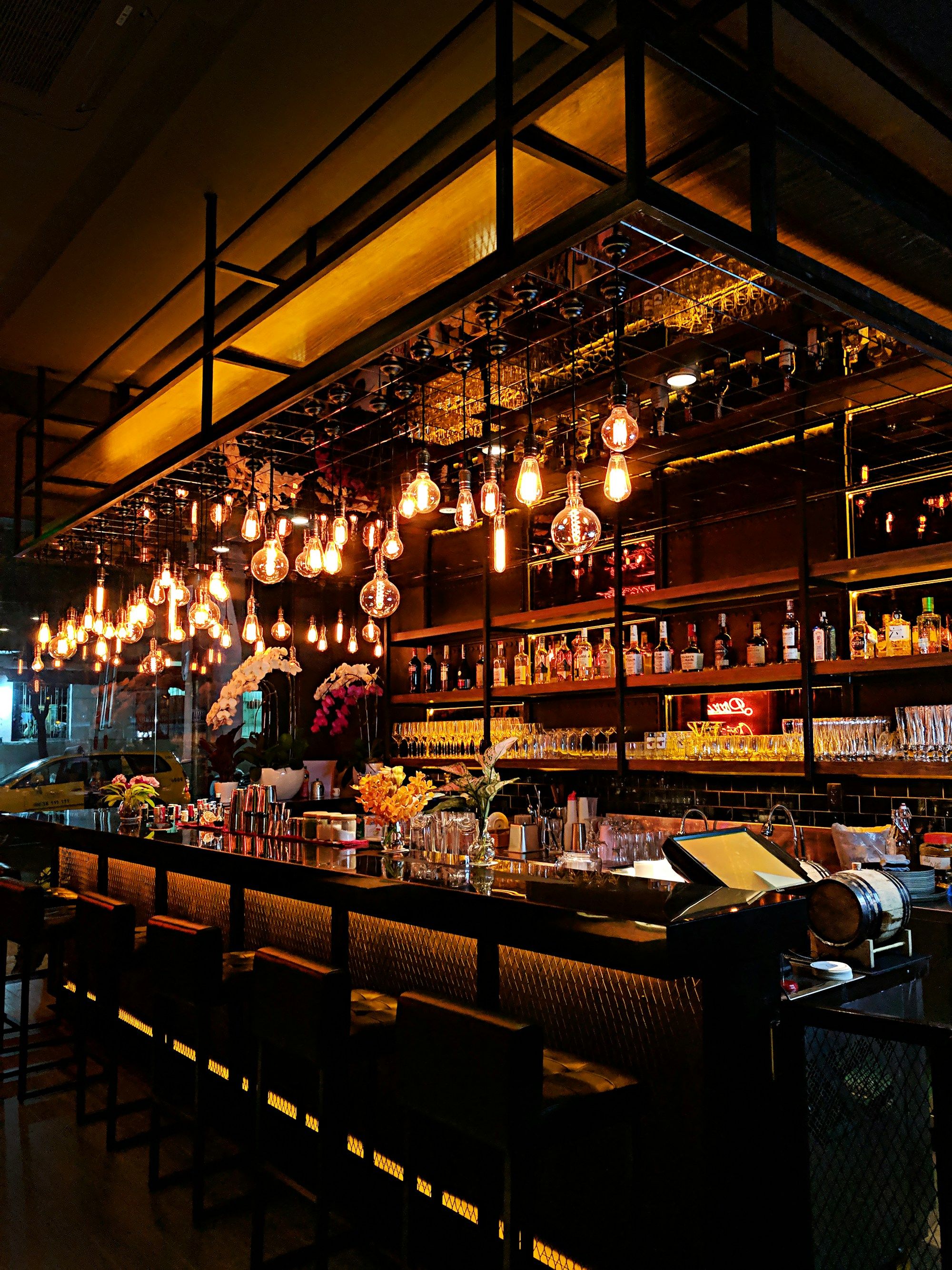 Salle de restaurant chaleureuse le soir, éclairée par des dizaines d'ampoules suspendues